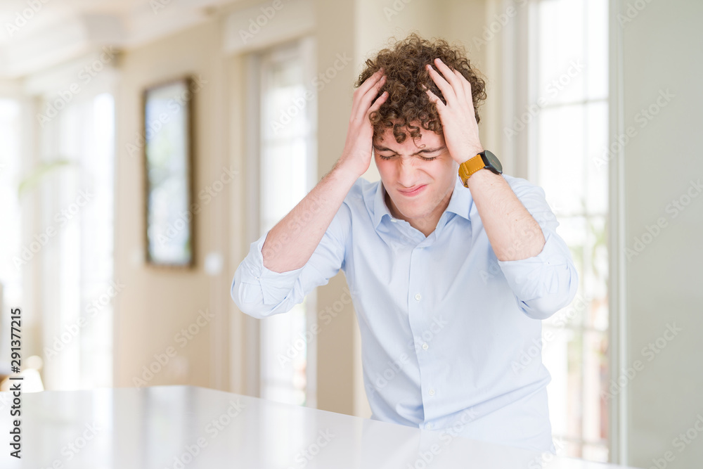 Young business man with curly read head suffering from headache desperate and stressed because pain and migraine. Hands on head. Young business man with curly read head suffering from headache desperate and stressed because pain and migraine. Hands on head.