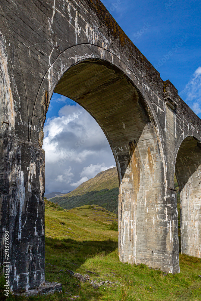 The Glenfinnan Viaduct in the Scottish Highlands, with rugged green mountains behind