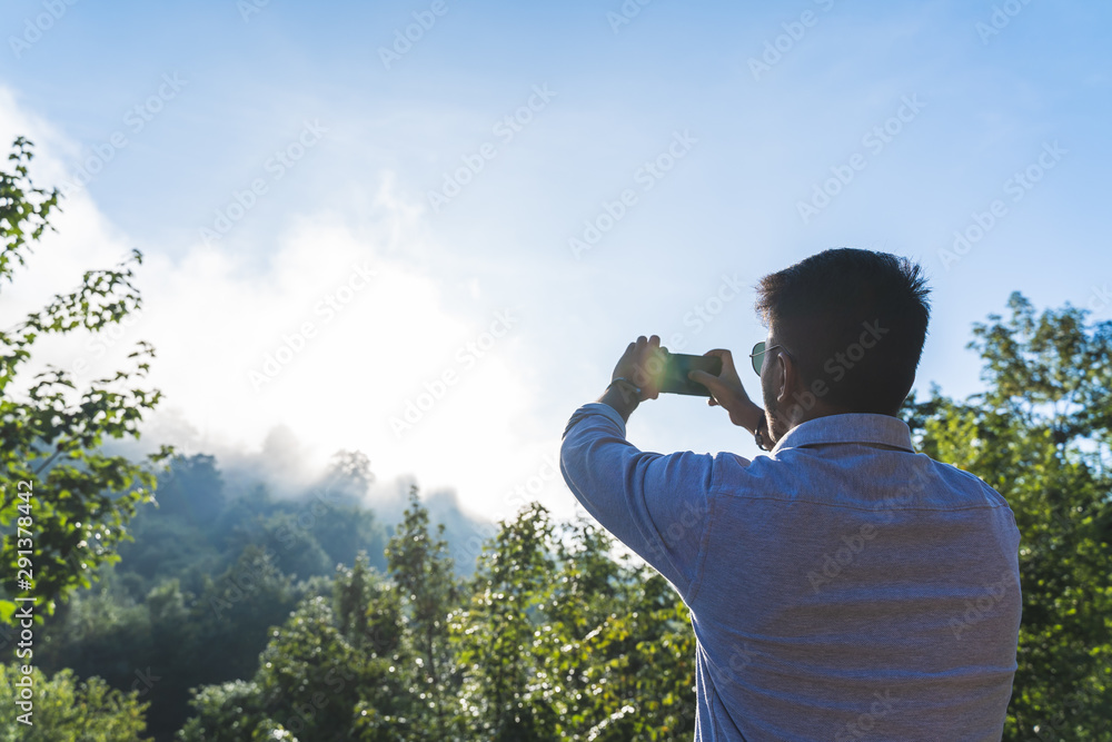 Fototapeta premium Indian Man Taking a Picture to the Sun Rising From the Mountain.