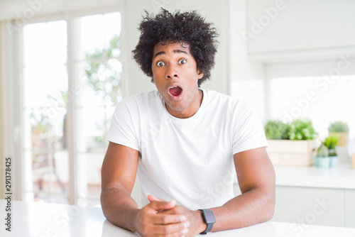 Young african american man wearing casual white t-shirt sitting at home afraid and shocked with surprise and amazed expression, fear and excited face.