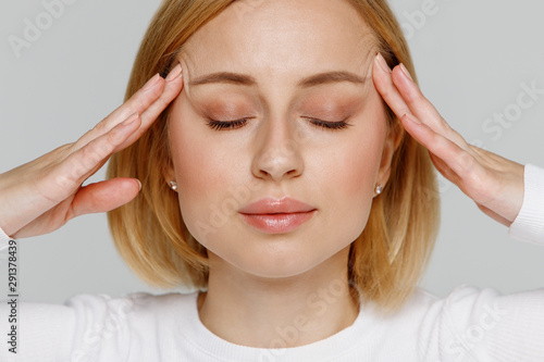 Wallpaper Mural Woman meditating and massaging her temples, closes eyes, relieves emotional stress and nervous tension, exhausted from overwork, isolated on grey background. Fatigued worker suffering from headache.  Torontodigital.ca