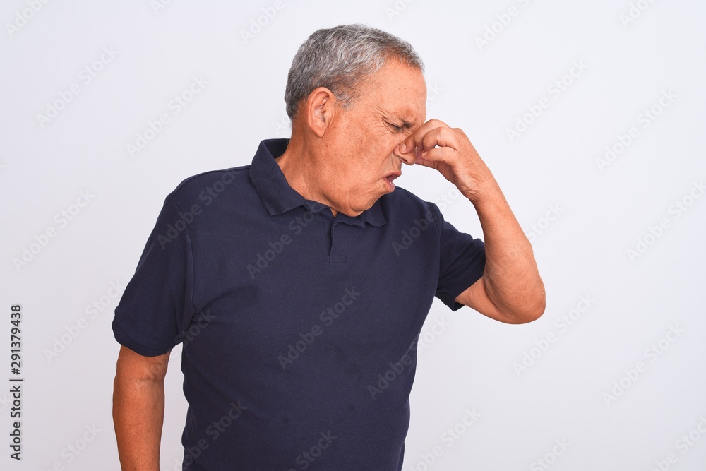 Senior grey-haired man wearing black casual polo standing over isolated white background smelling something stinky and disgusting, intolerable smell, holding breath with fingers on nose Senior grey-haired man wearing black casual polo standing over isolated white background smelling something stinky and disgusting, intolerable smell, holding breath with fingers on nose