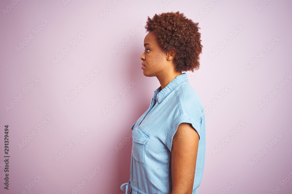Young beautiful african american woman with afro hair over isolated pink background looking to side, relax profile pose with natural face with confident smile. Young beautiful african american woman with afro hair over isolated pink background looking to side, relax profile pose with natural face with confident smile.