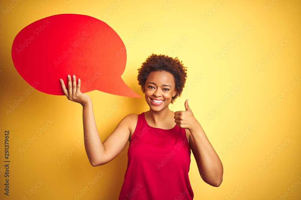Young african american woman holding speech bubble over yellow isolated background happy with big smile doing ok sign, thumb up with fingers, excellent sign Young african american woman holding speech bubble over yellow isolated background happy with big smile doing ok sign, thumb up with fingers, excellent sign