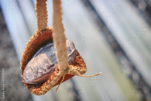 Roman slingshot of leather on the background of chain mail. Vintage weapons for throwing stones and lead. Retro outfit soldiers in ancient Rome, close-up.