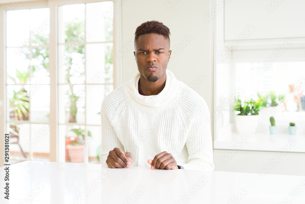 Handsome african american man on white table skeptic and nervous, frowning upset because of problem. Negative person.