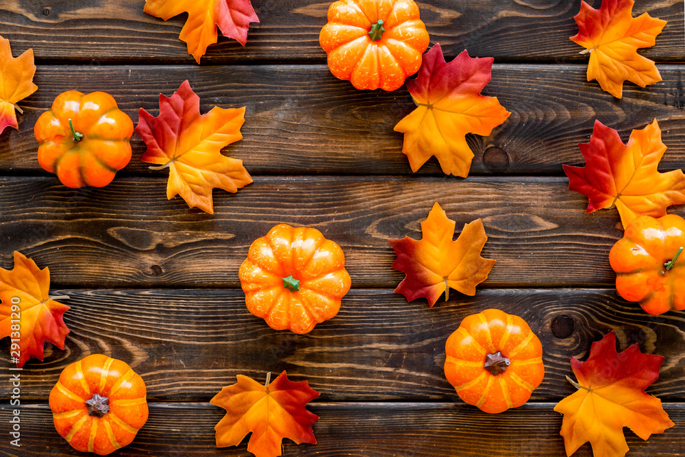 Autumn composition. Pattern with red and orange leaves and pumpkins on dark wooden background top view Autumn composition. Pattern with red and orange leaves and pumpkins on dark wooden background top view