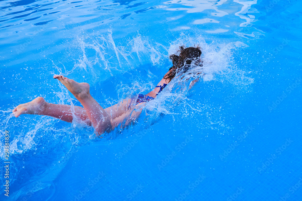 The girl jumps into the pool, the moment of immersion in the water and flying spray