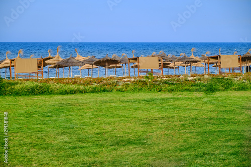 Sea view near green lawn and beach with straw umbrellas © Андрей Журавлев