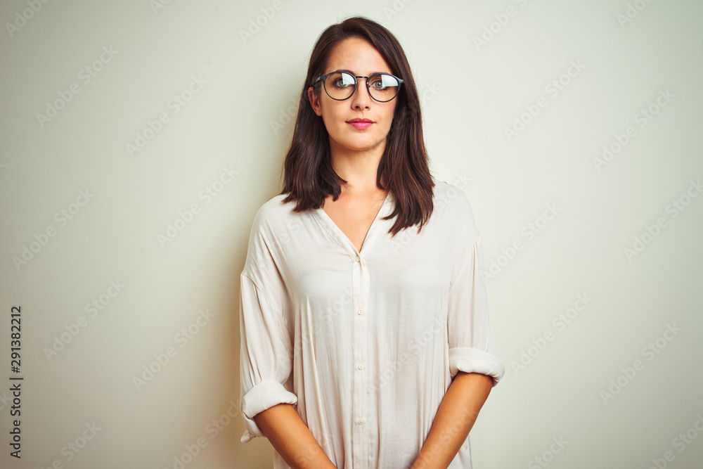 Young beautiful woman wearing shirt and glasses standing over white isolated background smiling in love showing heart symbol and shape with hands. Romantic concept. Young beautiful woman wearing shirt and glasses standing over white isolated background smiling in love showing heart symbol and shape with hands. Romantic concept.