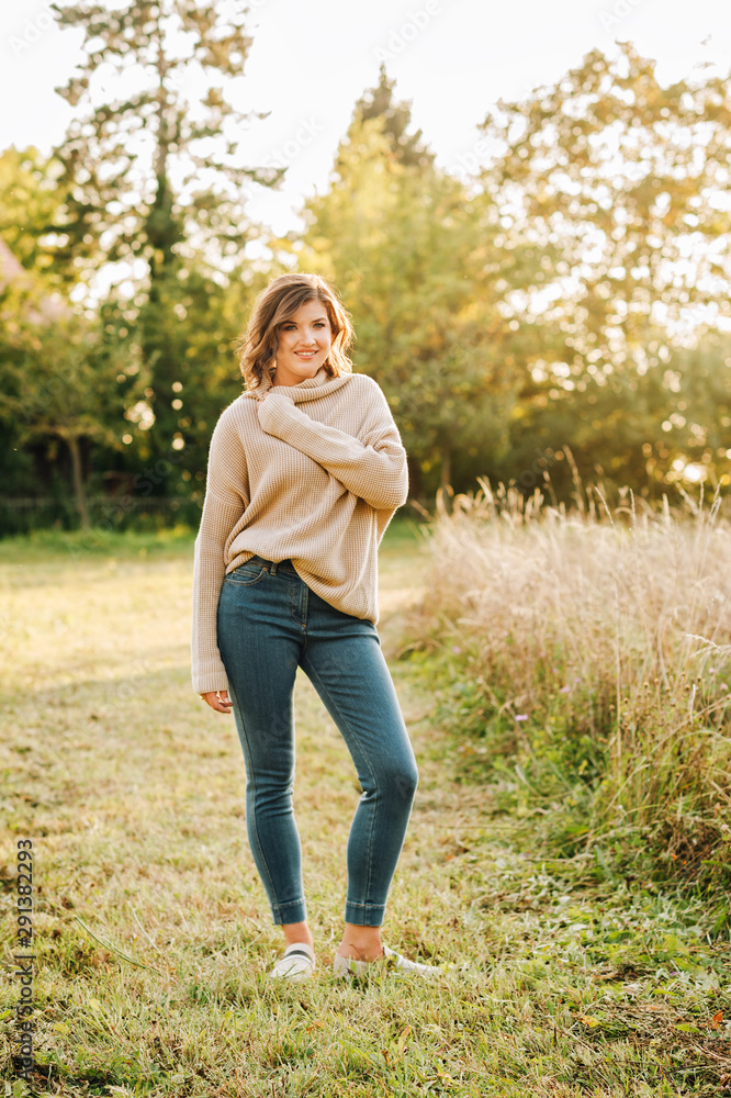 Outdoor portrait of beautiful young woman in the park, wearing warm knitted pullover Outdoor portrait of beautiful young woman in the park, wearing warm knitted pullover