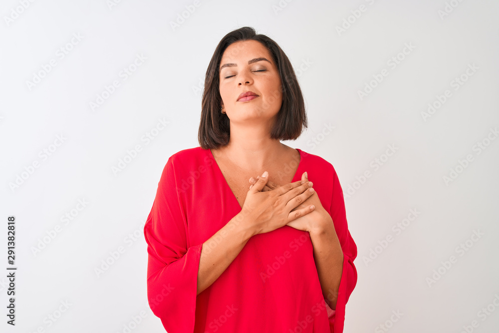 Young beautiful woman wearing red t-shirt standing over isolated white background smiling with hands on chest with closed eyes and grateful gesture on face. Health concept. Young beautiful woman wearing red t-shirt standing over isolated white background smiling with hands on chest with closed eyes and grateful gesture on face. Health concept.