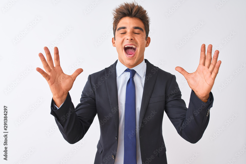 Young handsome businessman wearing suit standing over isolated white background celebrating mad and crazy for success with arms raised and closed eyes screaming excited. Winner concept Young handsome businessman wearing suit standing over isolated white background celebrating mad and crazy for success with arms raised and closed eyes screaming excited. Winner concept