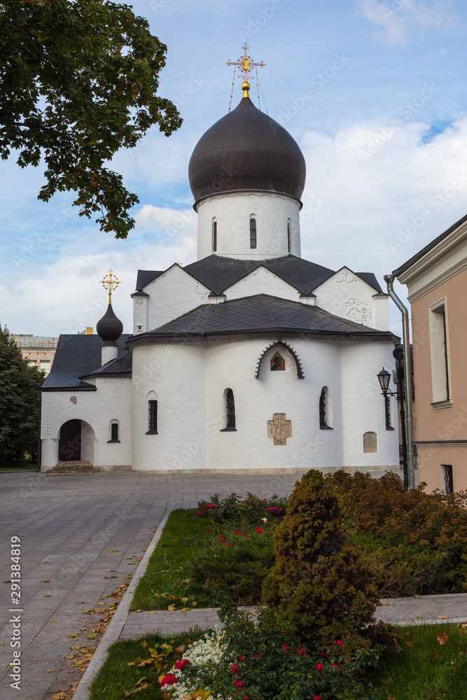 White-stone church in the Martha-Mariinsky monastery of mercy. In the foreground are flower beds with small trees