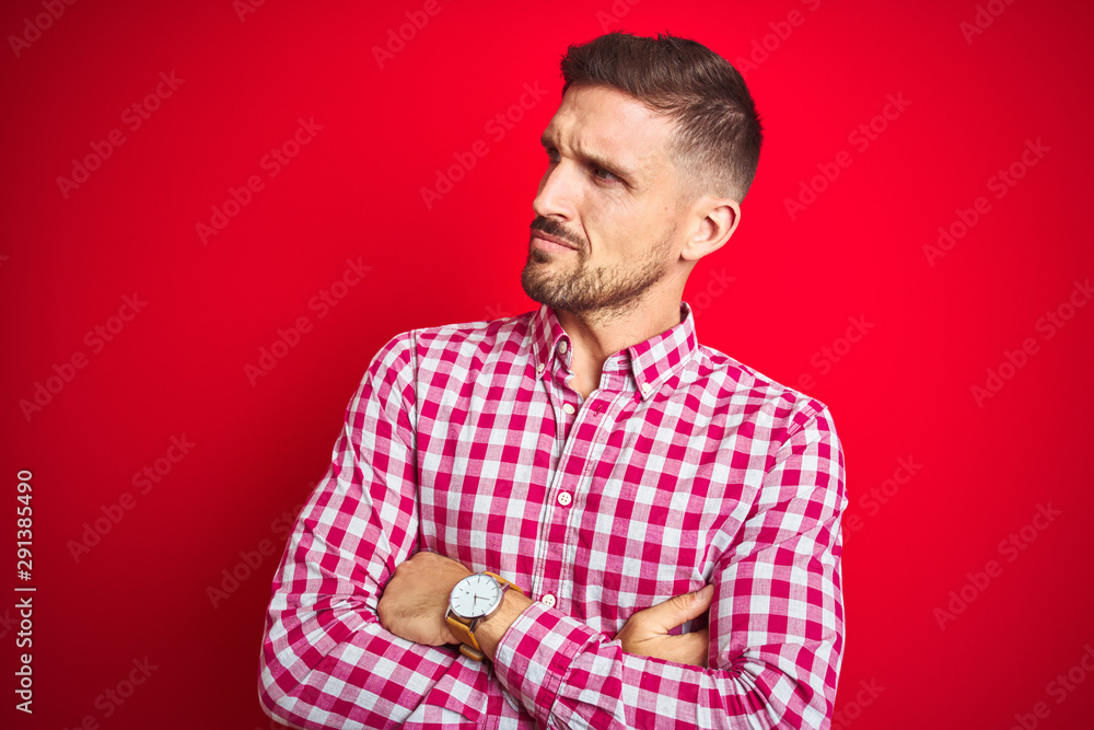 Young handsome man over red isolated background looking to the side with arms crossed convinced and confident Young handsome man over red isolated background looking to the side with arms crossed convinced and confident