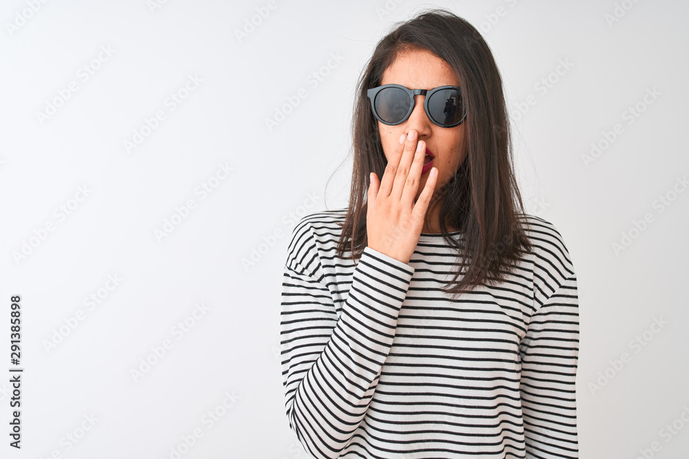 Chinese woman wearing striped t-shirt and sunglasses standing over isolated white background bored yawning tired covering mouth with hand. Restless and sleepiness. Chinese woman wearing striped t-shirt and sunglasses standing over isolated white background bored yawning tired covering mouth with hand. Restless and sleepiness.