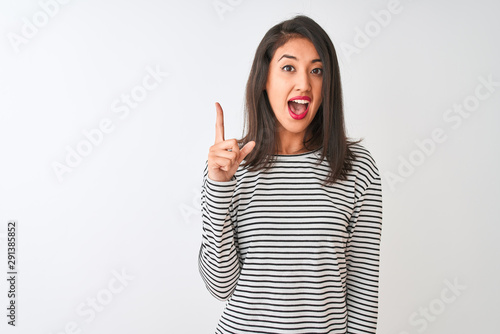 Young beautiful chinese woman wearing striped t-shirt standing over isolated white background pointing finger up with successful idea. Exited and happy. Number one. © Krakenimages.com