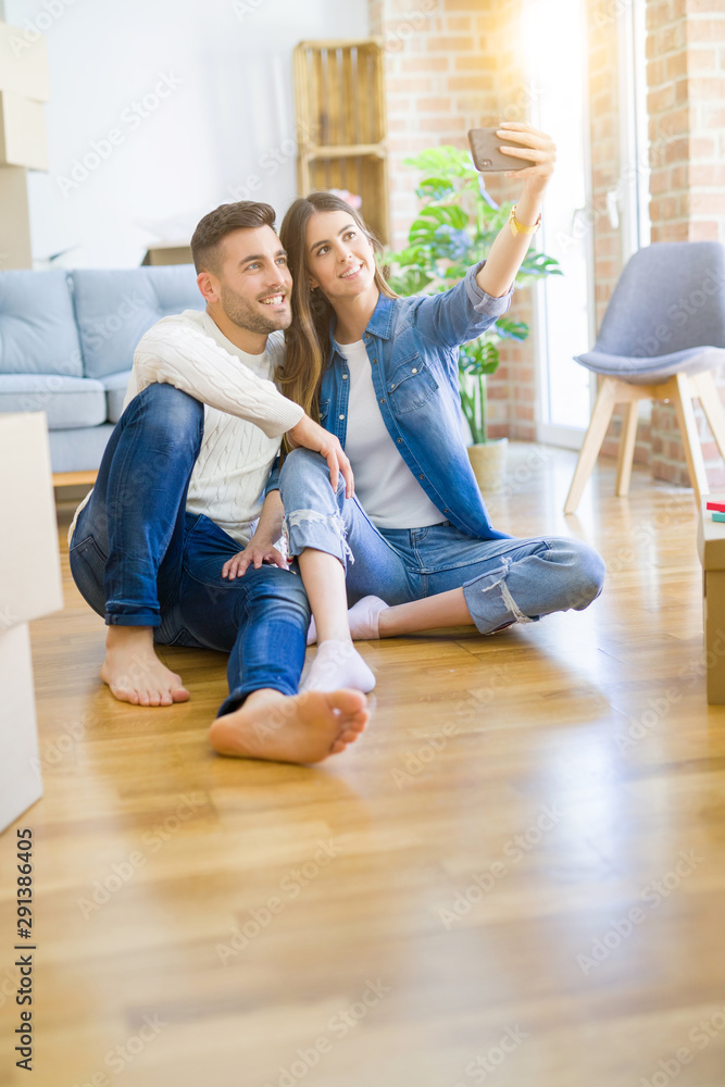 Young couple sitting on the floor of new house taking a selfie photo using smartphone, smiling happy for moving to new apartment Young couple sitting on the floor of new house taking a selfie photo using smartphone, smiling happy for moving to new apartment