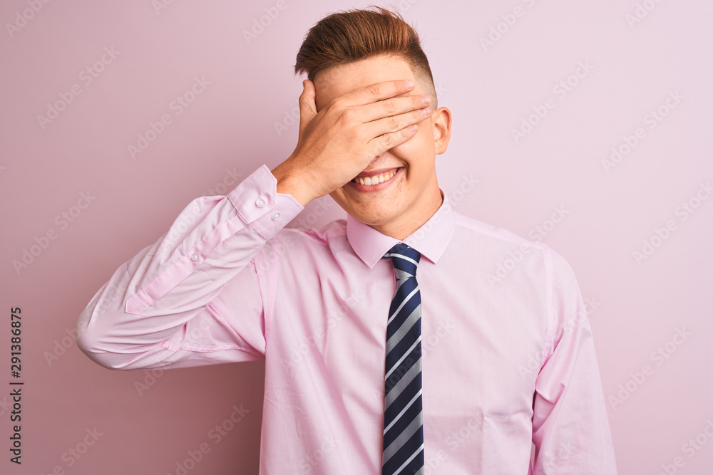 Young handsome businessman wearing shirt and tie standing over isolated pink background smiling and laughing with hand on face covering eyes for surprise. Blind concept. Young handsome businessman wearing shirt and tie standing over isolated pink background smiling and laughing with hand on face covering eyes for surprise. Blind concept.