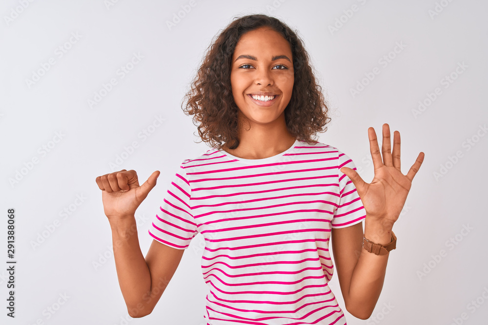 Young brazilian woman wearing pink striped t-shirt standing over isolated white background showing and pointing up with fingers number six while smiling confident and happy. Young brazilian woman wearing pink striped t-shirt standing over isolated white background showing and pointing up with fingers number six while smiling confident and happy.