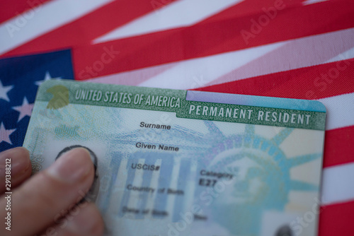 Permanent Resident Green card  of United states of America on flag of USA. Above close up view.
