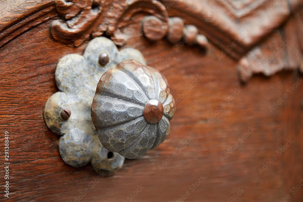 Old metal handle on a wooden door in an abandoned house. The round shape resembles a flower. On the subject there are small traces of rust on it. Home decoration. Selective focus Old metal handle on a wooden door in an abandoned house. The round shape resembles a flower. On the subject there are small traces of rust on it. Home decoration. Selective focus