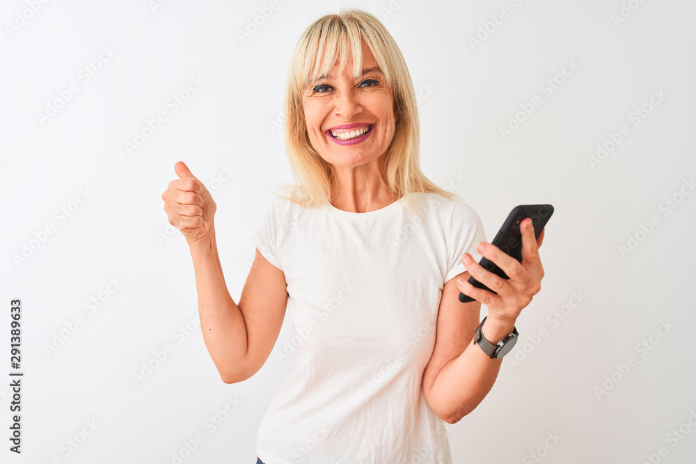 Middle age woman using smartphone standing over isolated white background happy with big smile doing ok sign, thumb up with fingers, excellent sign Middle age woman using smartphone standing over isolated white background happy with big smile doing ok sign, thumb up with fingers, excellent sign