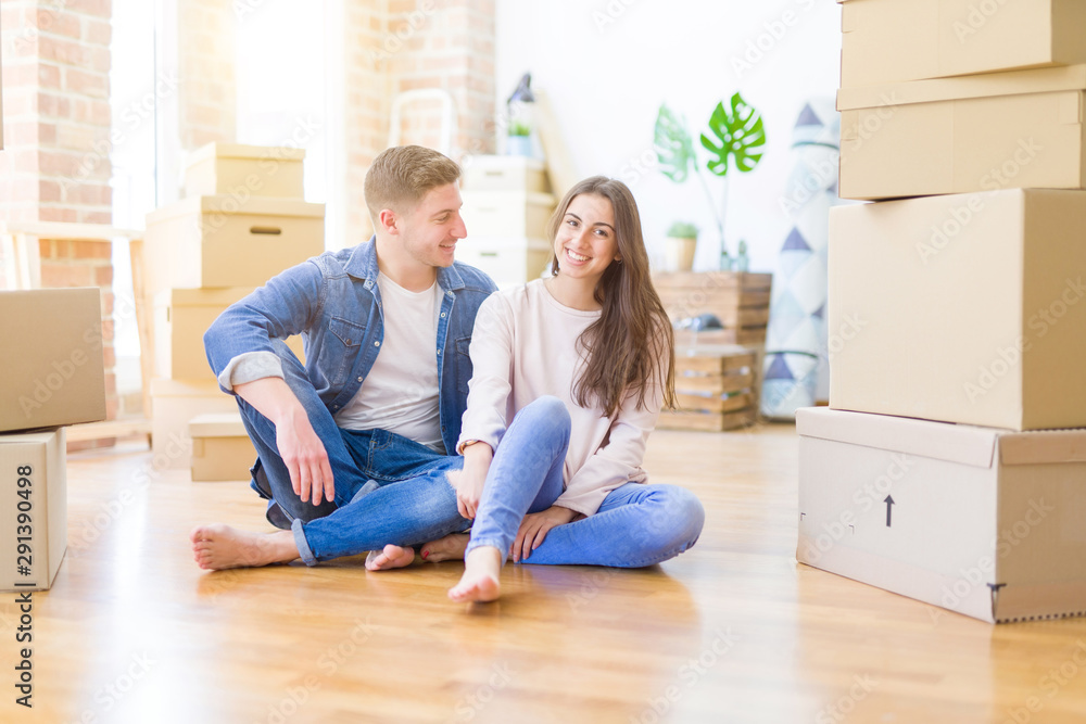 Young beautiful couple relaxing sitting on the floor around cardboard boxes at home, smiling happy moving to a new house Young beautiful couple relaxing sitting on the floor around cardboard boxes at home, smiling happy moving to a new house