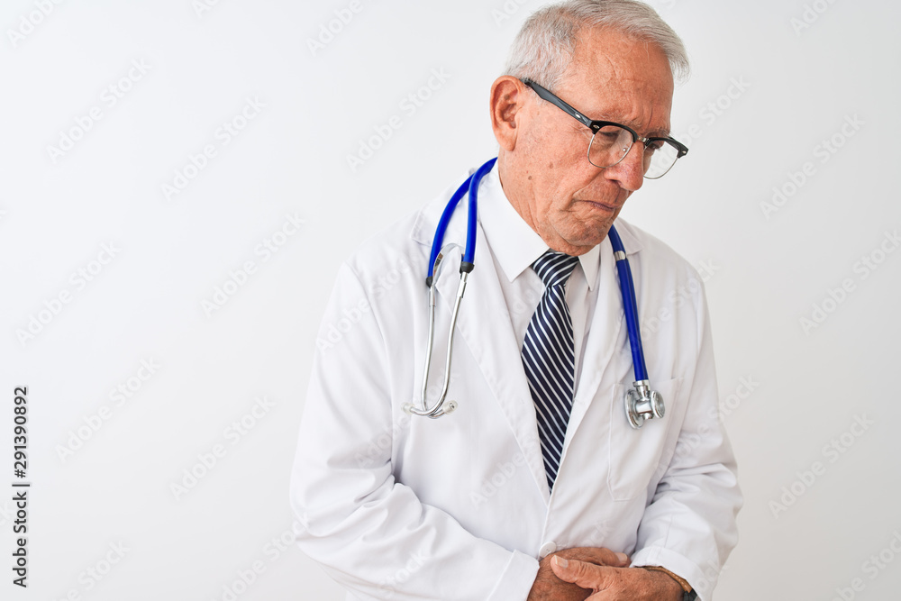 Senior grey-haired doctor man wearing stethoscope standing over isolated white background with hand on stomach because nausea, painful disease feeling unwell. Ache concept. Senior grey-haired doctor man wearing stethoscope standing over isolated white background with hand on stomach because nausea, painful disease feeling unwell. Ache concept.