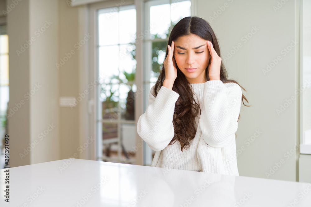 Young beautiful woman at home on white table with hand on head for pain in head because stress. Suffering migraine.