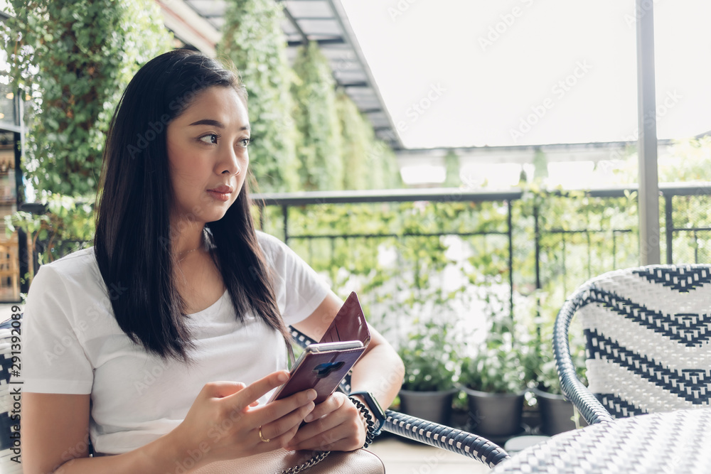 Asian woman is using her smartphone while sitting in cafe. Asian woman is using her smartphone while sitting in cafe.