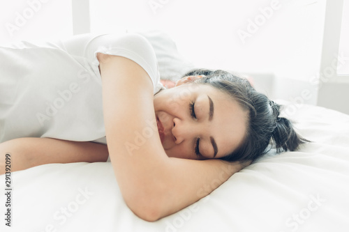 Asian woman is sleeping on her white cozy bed.