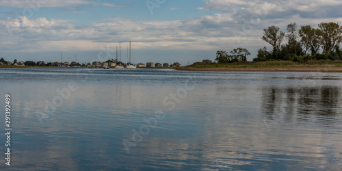 Island at river mouth in coastal town in New England, USA in late summer showing  vivid reflections of sky and structures above horizon