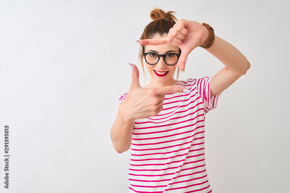 Redhead woman wearing glasses striped t-shirt and pigtail over isolated white background smiling making frame with hands and fingers with happy face. Creativity and photography concept. Redhead woman wearing glasses striped t-shirt and pigtail over isolated white background smiling making frame with hands and fingers with happy face. Creativity and photography concept.