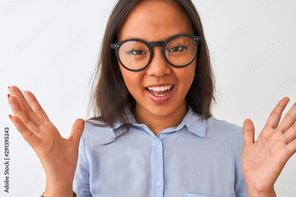Young chinese woman wearing shirt and glasses standing over isolated white background very happy and excited, winner expression celebrating victory screaming with big smile and raised hands Young chinese woman wearing shirt and glasses standing over isolated white background very happy and excited, winner expression celebrating victory screaming with big smile and raised hands