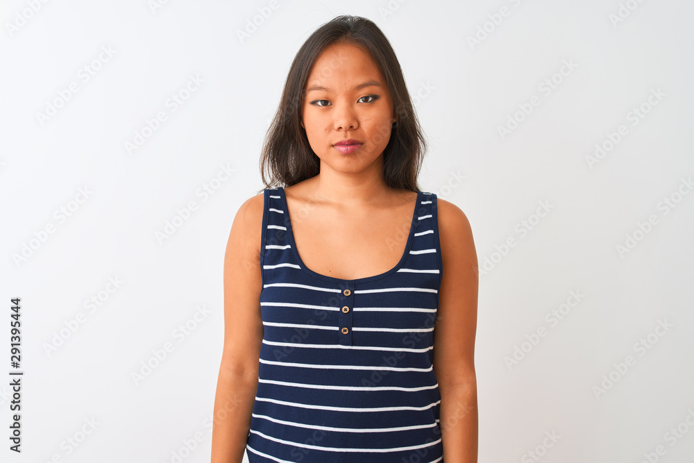 Young chinese woman wearing striped t-shirt standing over isolated white background with serious expression on face. Simple and natural looking at the camera. Young chinese woman wearing striped t-shirt standing over isolated white background with serious expression on face. Simple and natural looking at the camera.