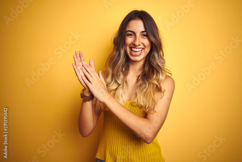 Young beautiful woman wearing t-shirt over yellow isolated background clapping and applauding happy and joyful, smiling proud hands together