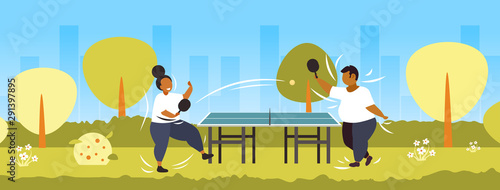 fat obese couple playing ping pong table tennis african american overweight man woman having fun weight loss concept public park landscape background flat full length horizontal