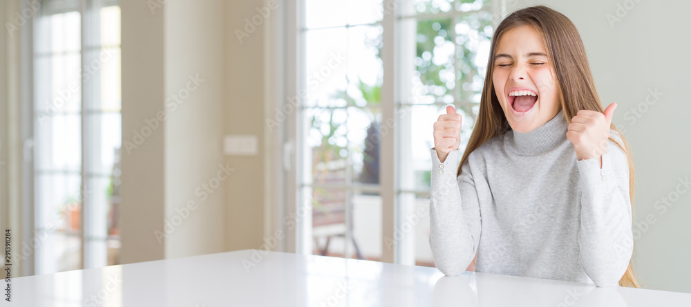 Wide angle picture of beautiful young girl kid wearing casual sweater excited for success with arms raised celebrating victory smiling. Winner concept. Wide angle picture of beautiful young girl kid wearing casual sweater excited for success with arms raised celebrating victory smiling. Winner concept.