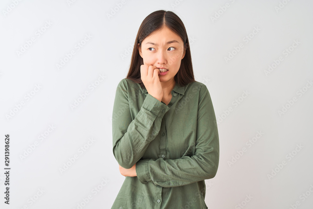 Young chinese woman wearing casual green shirt standing over isolated white background looking stressed and nervous with hands on mouth biting nails. Anxiety problem. Young chinese woman wearing casual green shirt standing over isolated white background looking stressed and nervous with hands on mouth biting nails. Anxiety problem.