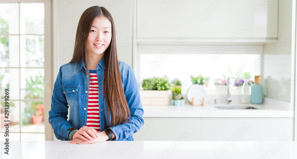 Beautiful Asian woman wearing denim jacket on white table with a happy and cool smile on face. Lucky person.