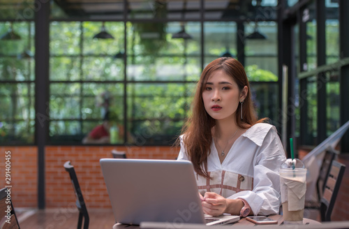 Young businesswoman with a coffee cup working online on laptop while sitting in coffee shop.