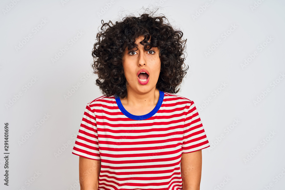 Young arab woman with curly hair wearing striped t-shirt over isolated white background afraid and shocked with surprise expression, fear and excited face. Young arab woman with curly hair wearing striped t-shirt over isolated white background afraid and shocked with surprise expression, fear and excited face.