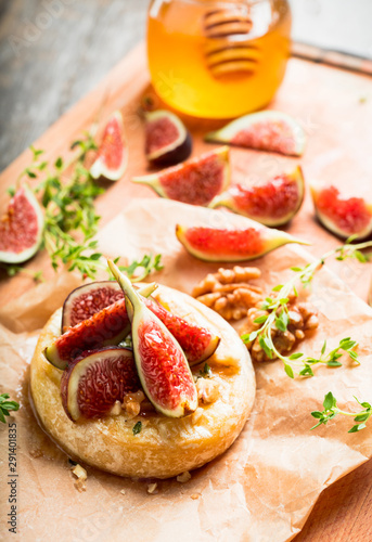 Baked camembert cheese with figs, walnuts, honey and thyme on the rustc background. Selective focus. Shallow depth of field.