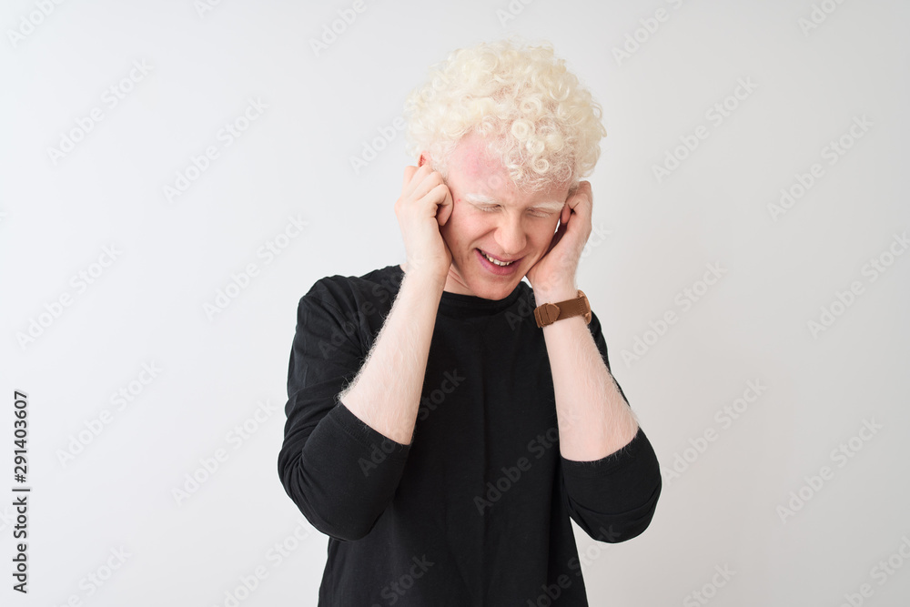 Young albino blond man wearing black t-shirt standing over isolated white background covering ears with fingers with annoyed expression for the noise of loud music. Deaf concept. Young albino blond man wearing black t-shirt standing over isolated white background covering ears with fingers with annoyed expression for the noise of loud music. Deaf concept.