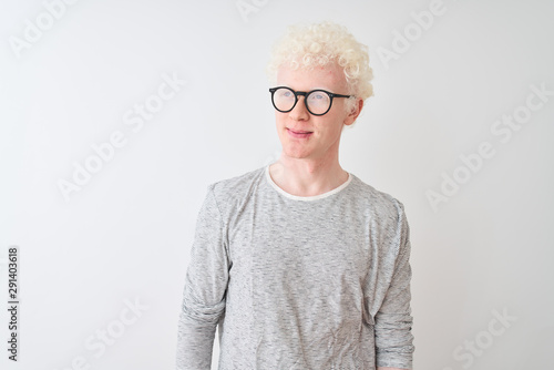 Young albino blond man wearing striped t-shirt and glasses over isolated white background smiling looking to the side and staring away thinking.