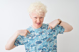Young albino blond man wearing casual t-shirt standing over isolated white background looking confident with smile on face, pointing oneself with fingers proud and happy.