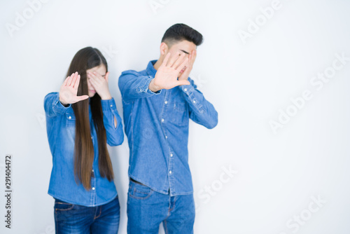 Beautiful young asian couple over white isolated background covering eyes with hands and doing stop gesture with sad and fear expression. Embarrassed and negative concept.