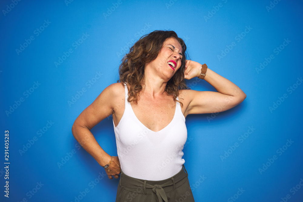 Middle age senior woman with curly hair standing over blue isolated background stretching back, tired and relaxed, sleepy and yawning for early morning Middle age senior woman with curly hair standing over blue isolated background stretching back, tired and relaxed, sleepy and yawning for early morning