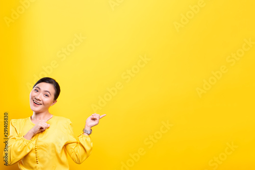 Woman pointing to copy space isolated over yellow background